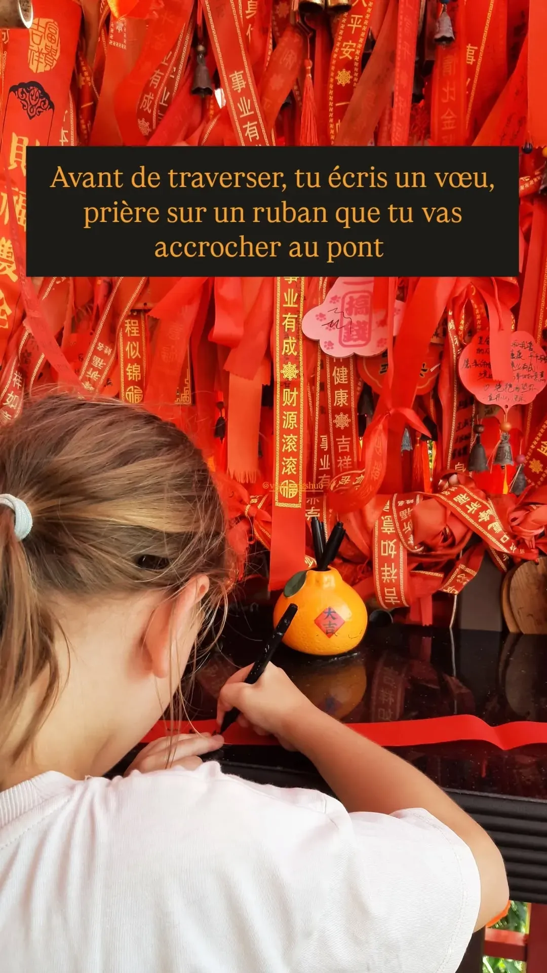 Visitor writing a wish on a red ribbon before crossing the bridge at Ruyi Peak, Yangshuo, China